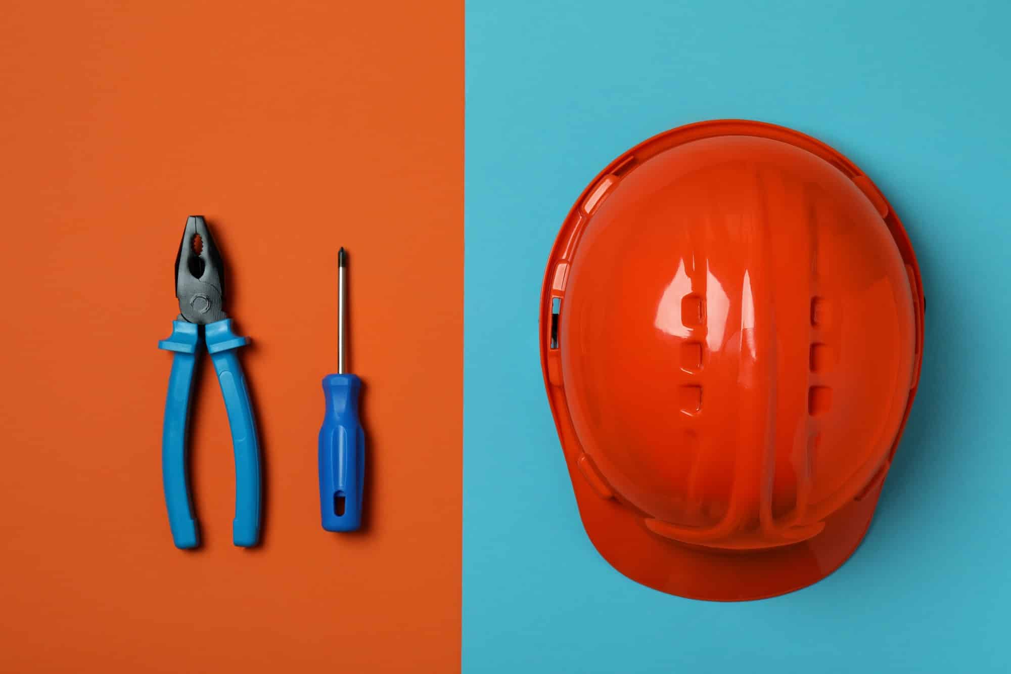 Hard hat and tools on two tone background, top view